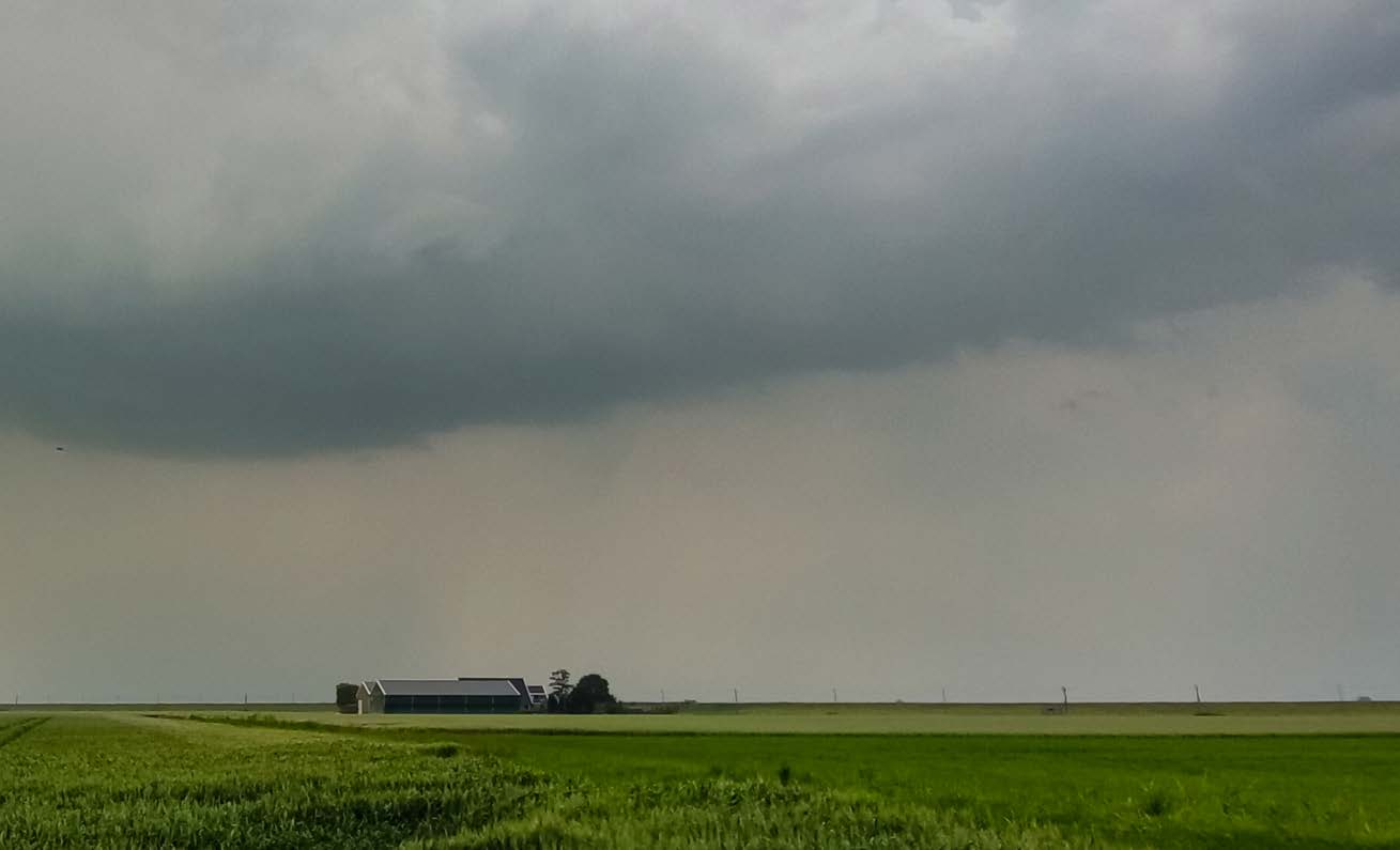 Donkere onweerslucht boven landbouwgebied als symbool voor verborgen criminaliteit in het buitengebied